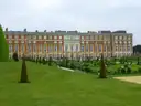 Hampton Court Palace's red-brick east front behind lawns and clipped yew trees