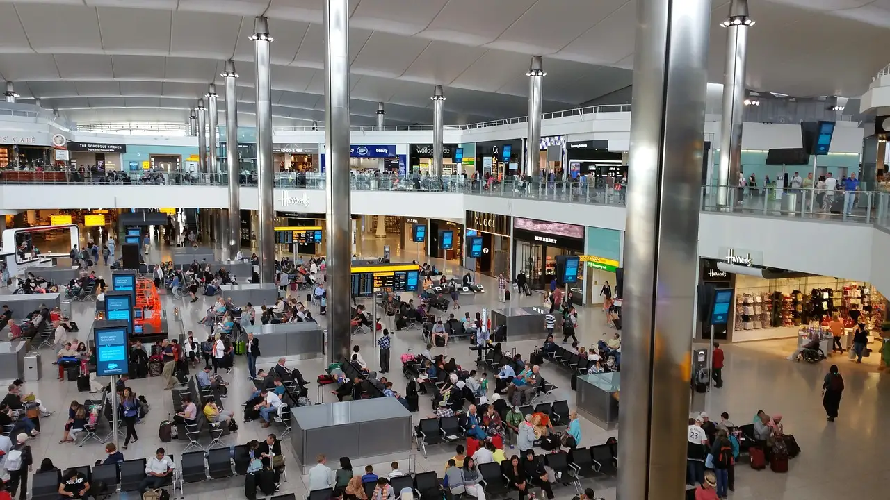 The busy departures hall of a Heathrow terminal with travellers on several levels under a bright roof