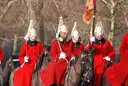 Household Cavalry troopers in red tunics and plumed helmets on horseback