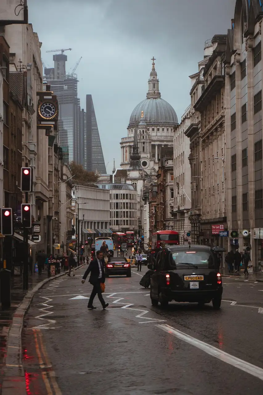 A wet London street at dusk with a black taxi and the dome of St Paul's in the distance