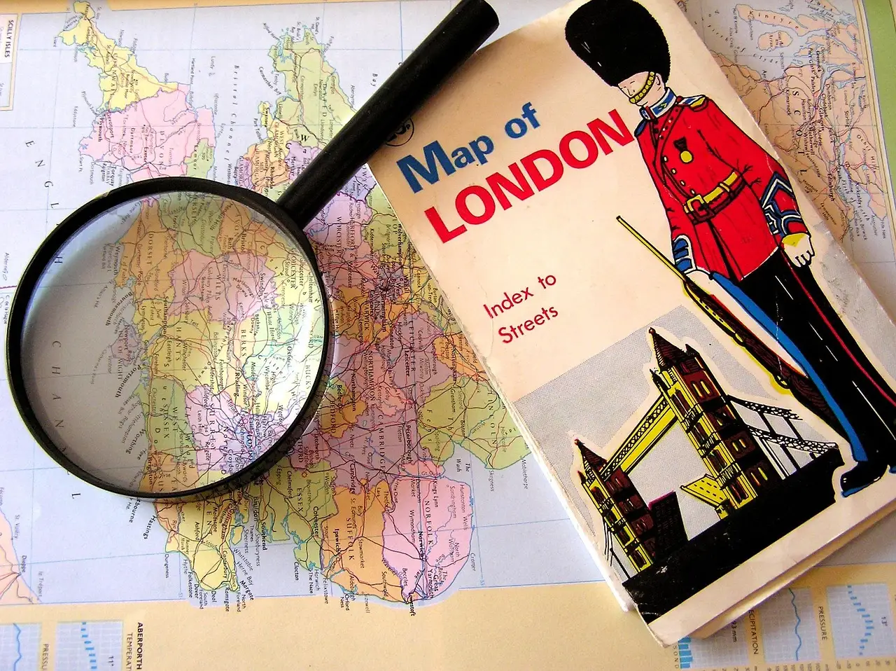 A vintage London map with a magnifying glass resting on it, planning a trip