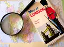 A vintage London map with a magnifying glass resting on it, planning a trip