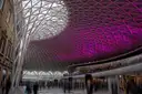 King's Cross station concourse with its lattice roof lit purple