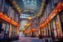 Leadenhall Market arcade with painted ironwork, glass roof and lit shop fronts