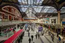The busy concourse of a London railway station under an iron-and-glass roof