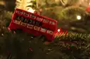 A red London bus ornament on a Christmas tree