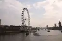 The London Eye beside the Thames, with a passenger boat on the river