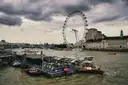 A river boat at the pier beside the London Eye under grey clouds