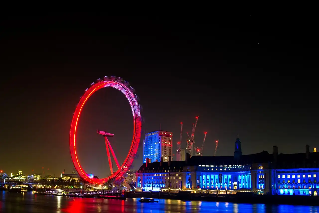 The London Eye lit red at night beside County Hall