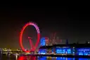 The London Eye lit red at night beside County Hall