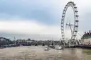 The London Eye beside the River Thames, with boats moored on the water below