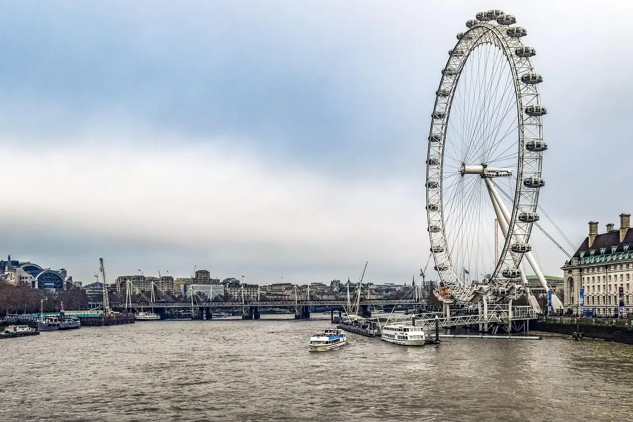 The London Eye beside the River Thames, with boats moored on the water below