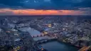 London from high above at dusk, with the Thames and its bridges winding through the city