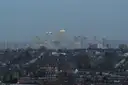 Rows of terraced houses stretching toward the towers of Canary Wharf at dusk, seen from Alexandra Palace in London