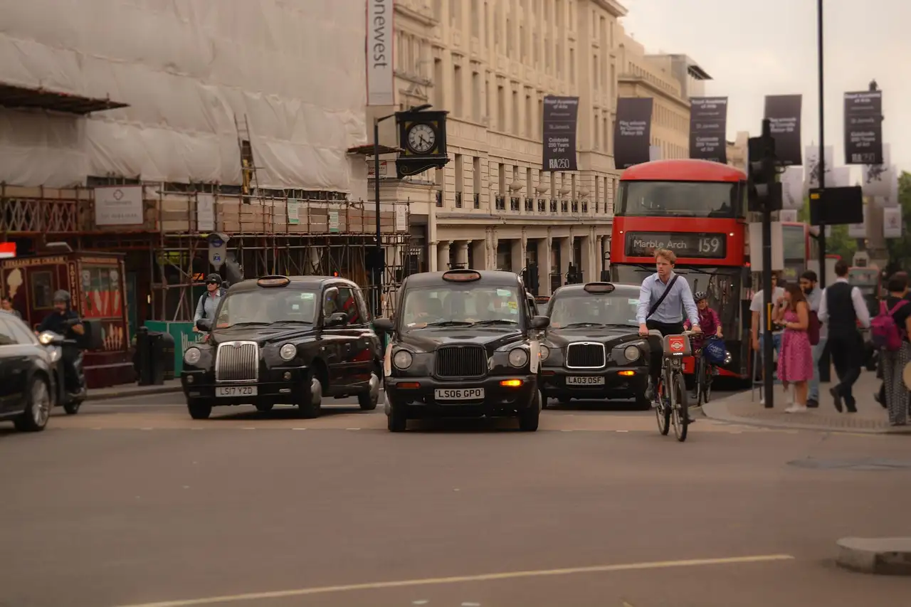 Central London street with black cabs, a cyclist and a red double-decker bus