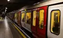A red-and-white Underground train pulling in along a curved platform with a yellow safety line