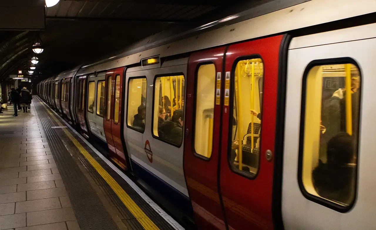 A red-and-white Underground train pulling in along a curved platform with a yellow safety line
