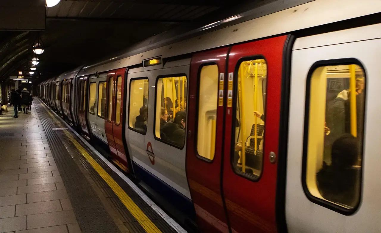 A red-and-white Underground train pulling in along a curved platform with a yellow safety line
