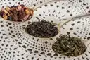 Three spoons of loose-leaf tea blends on a lace cloth