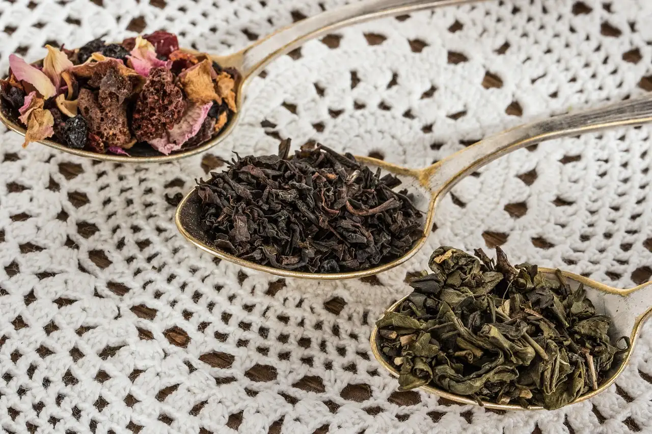Three spoons of loose-leaf tea blends on a lace cloth