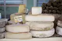 Whole and cut cheeses stacked on a market stall