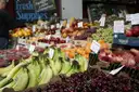 A market stall piled with bananas, cherries and apples