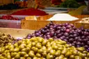 Trays of green and purple olives on a market stall