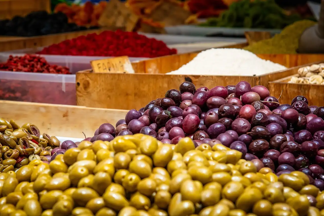 Trays of green and purple olives on a market stall