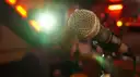 A microphone on a stand with the lights of a bar blurred behind