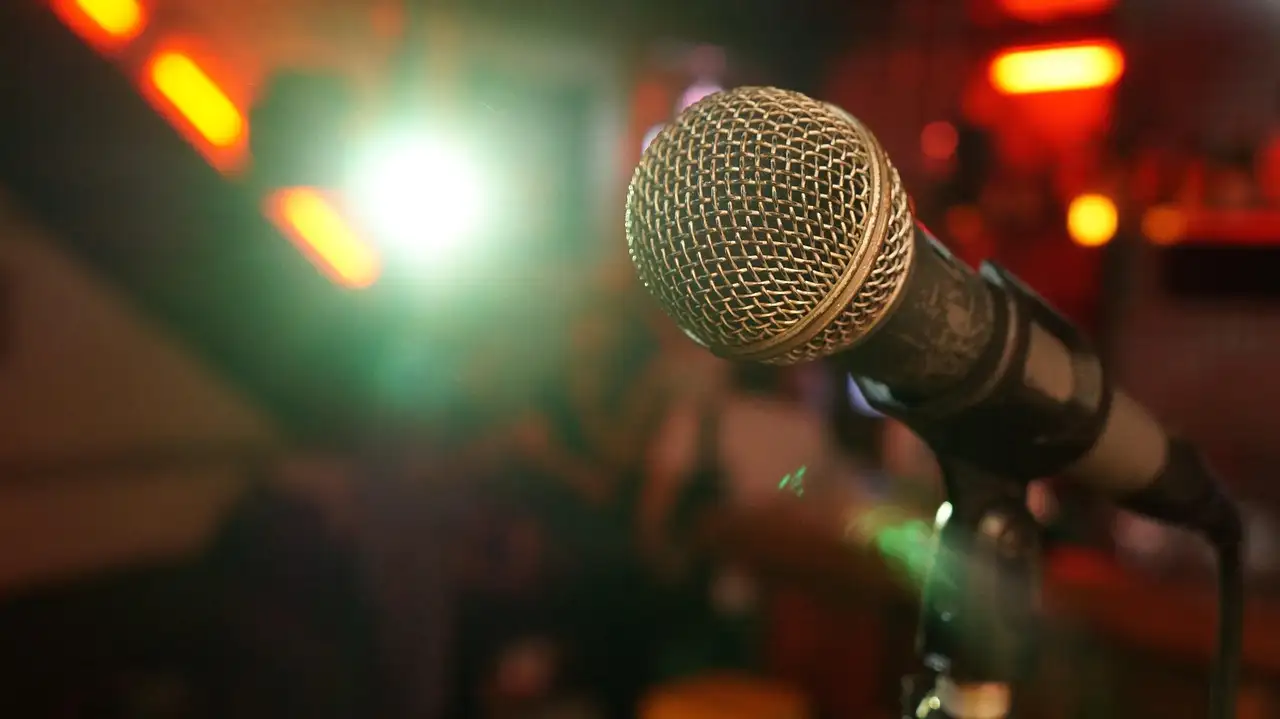A microphone on a stand with the lights of a bar blurred behind