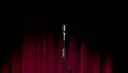 A single microphone on a stand in front of a red stage curtain
