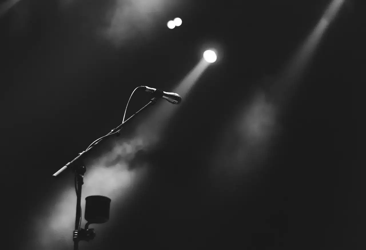 A microphone under a spotlight in a dark, hazy room