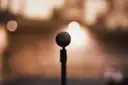 A microphone on a stand against warm, blurred lights