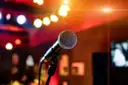 A microphone in front of warm, blurred stage lights