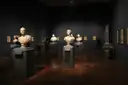 Marble busts on plinths in a dimly lit museum gallery