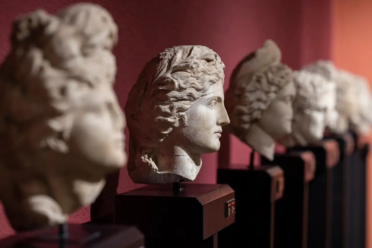 A row of carved marble heads against a dark red museum wall