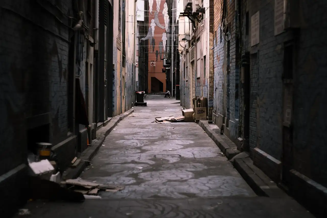 A narrow, gloomy back alley between tall brick buildings