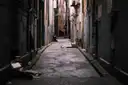 A narrow, gloomy back alley between tall brick buildings