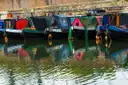 Colourful narrowboats moored side by side on a canal