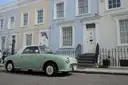 Vintage green car parked outside pastel terraced houses in Notting Hill