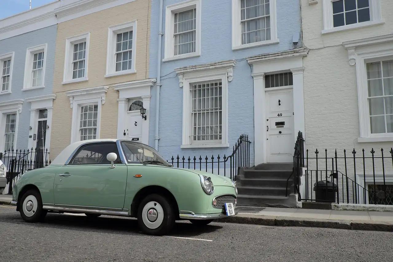 Vintage green car parked outside pastel terraced houses in Notting Hill