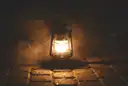 An old oil lantern glowing on cobblestones in the dark