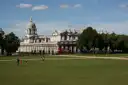 A domed building of the Old Royal Naval College across a wide lawn in Greenwich