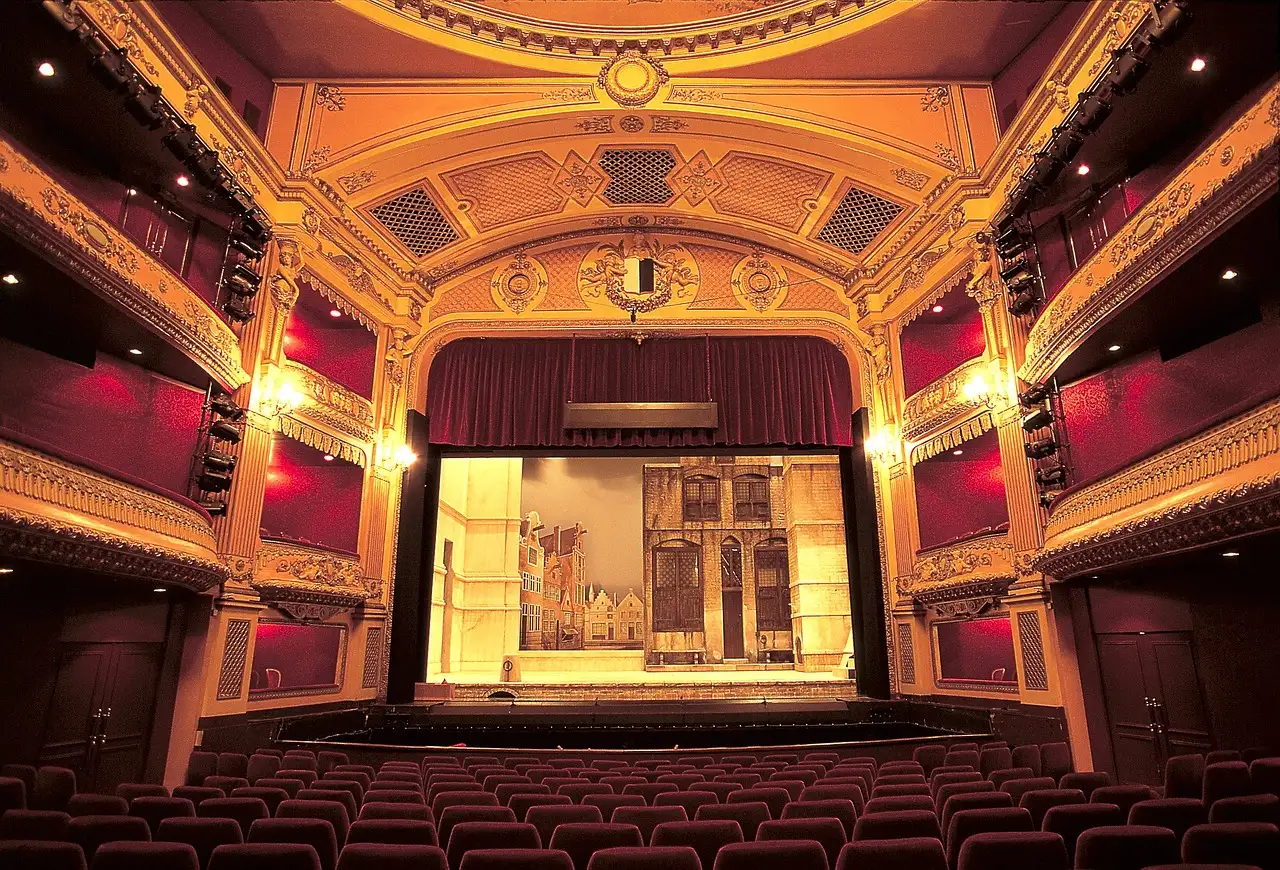An ornate gilded theatre with red boxes and a lit stage