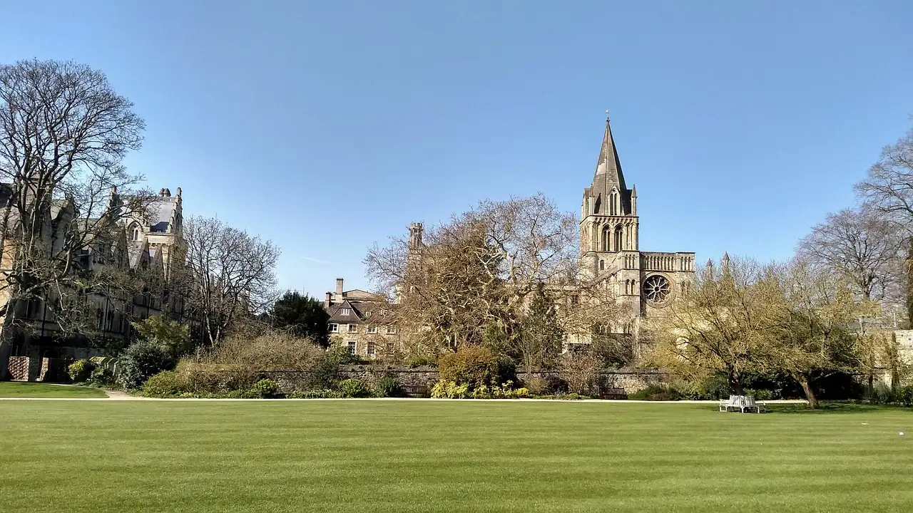 Christ Church college and spire seen across a green meadow in Oxford