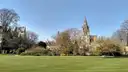 Christ Church college and spire seen across a green meadow in Oxford