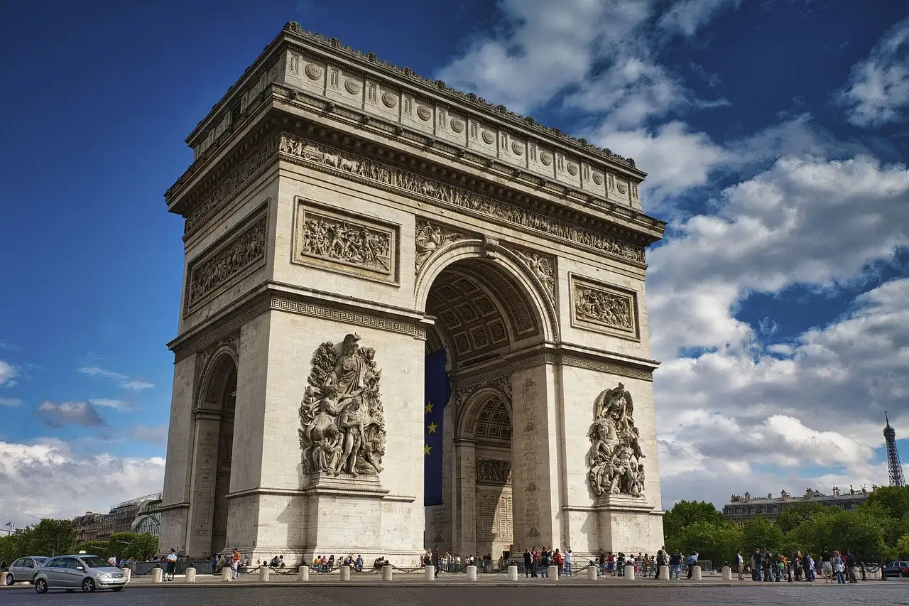 The Arc de Triomphe in Paris under a blue sky with white clouds