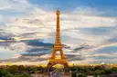 Eiffel Tower lit golden against a cloudy evening sky