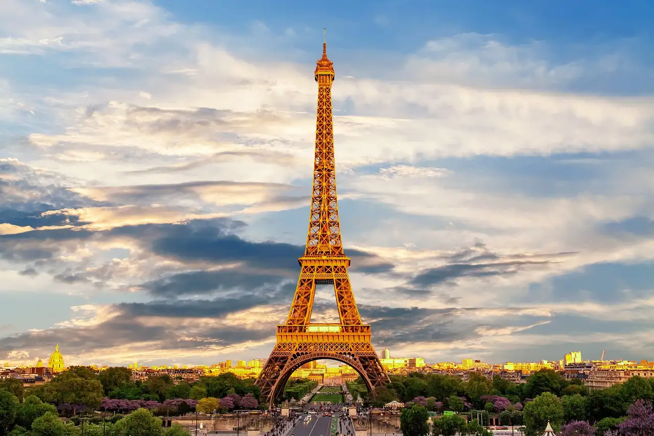 Eiffel Tower lit golden against a cloudy evening sky