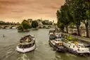 Tour boat on the Seine in Paris beside moored barges at sunset